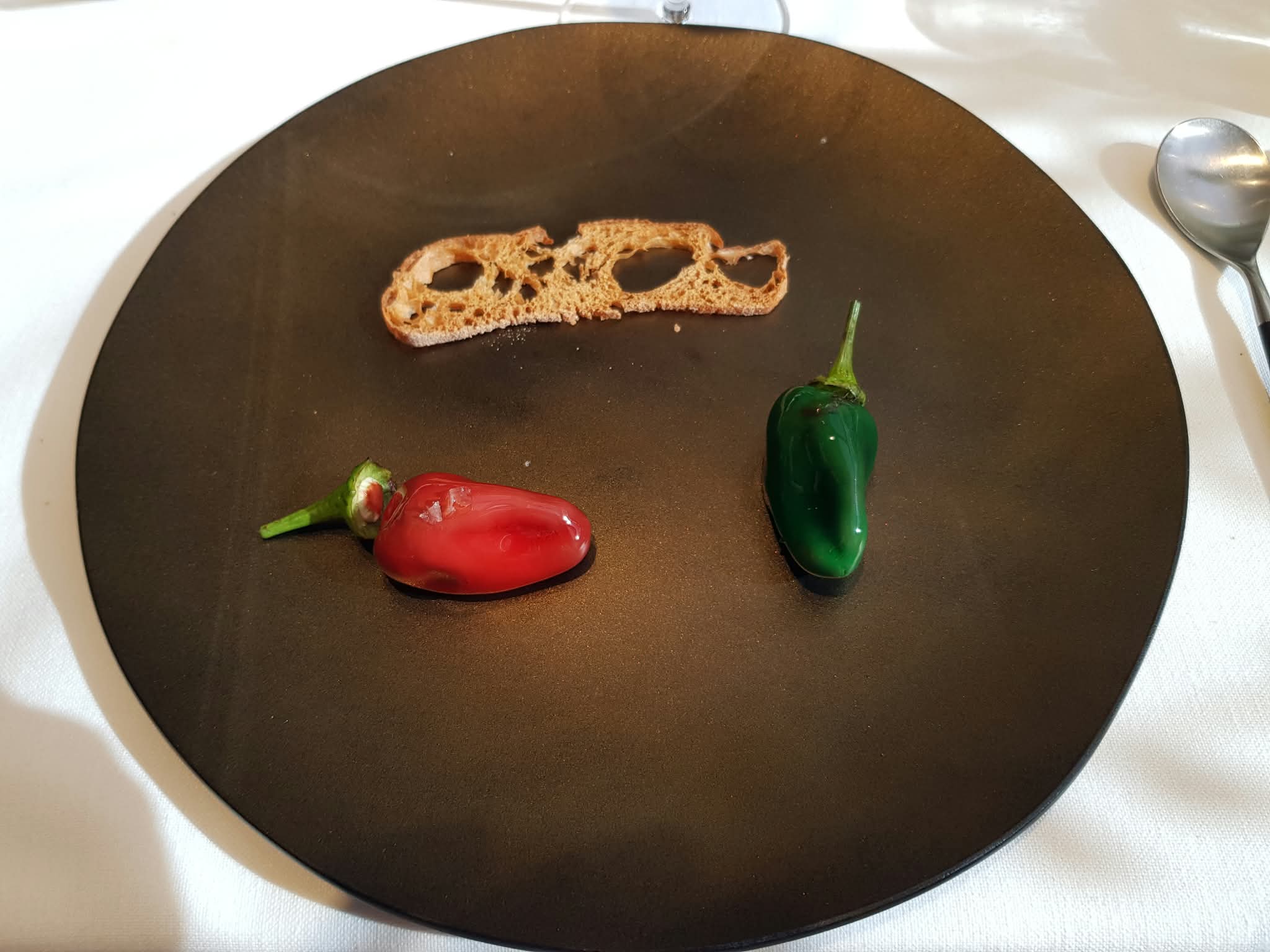 Two peppers on a dark plate at Disfrutar